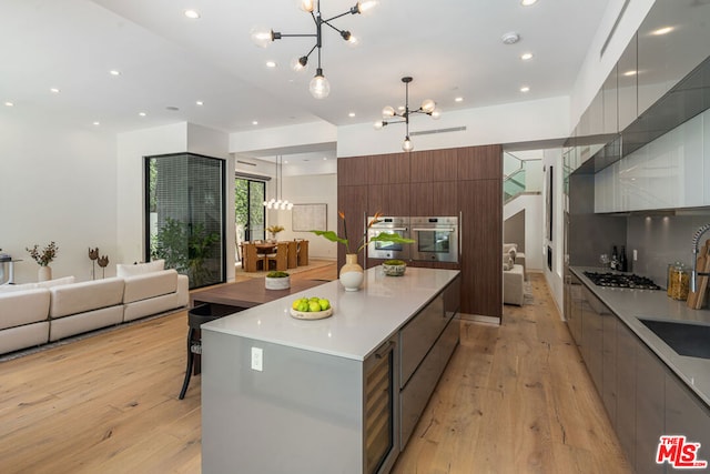 kitchen featuring light hardwood / wood-style floors, a large island, pendant lighting, and a notable chandelier