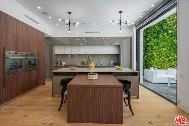 kitchen featuring stainless steel appliances, white cabinets, hanging light fixtures, and a kitchen bar