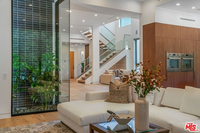 living room featuring a towering ceiling and light wood-type flooring