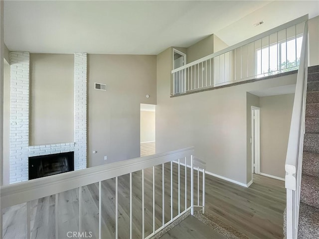 hallway featuring a high ceiling, wood finished floors, visible vents, baseboards, and stairway