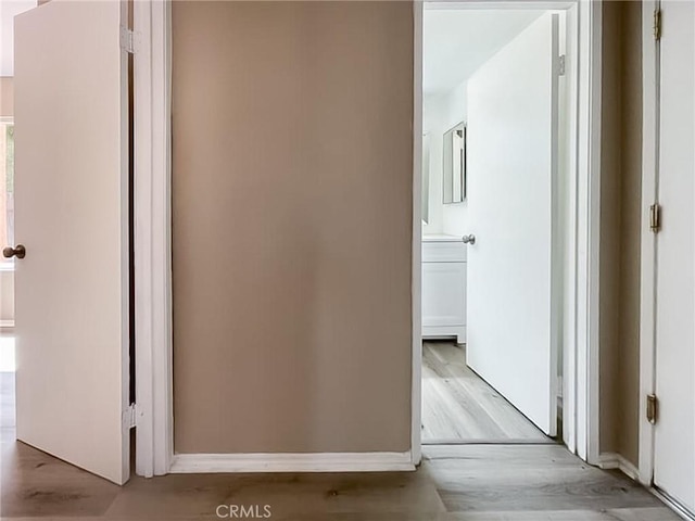 corridor featuring light wood-type flooring and baseboards