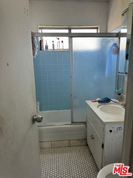 full bathroom with tile patterned flooring, toilet, vanity, and bath / shower combo with glass door