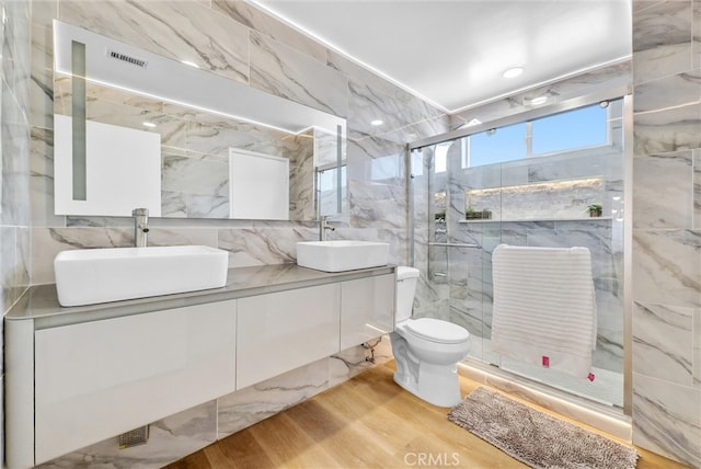 bathroom featuring vanity, wood-type flooring, walk in shower, tile walls, and toilet