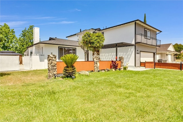 back of house with a balcony, a yard, and a garage