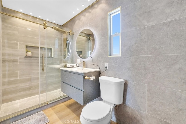 bathroom with vanity, hardwood / wood-style flooring, walk in shower, tile walls, and toilet