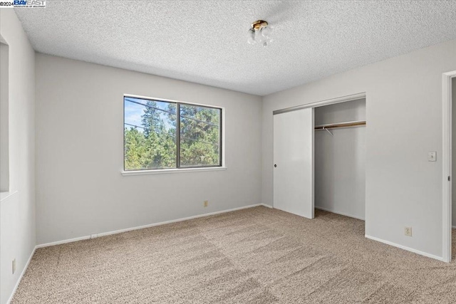 unfurnished bedroom with carpet floors, a textured ceiling, and a closet