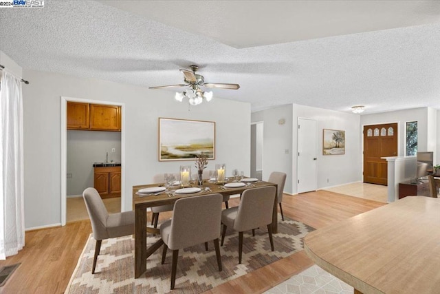 dining room with light hardwood / wood-style flooring, ceiling fan, a healthy amount of sunlight, and a textured ceiling