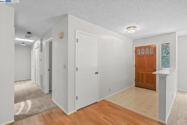 entrance foyer with light hardwood / wood-style floors and a textured ceiling