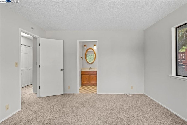 carpeted spare room with a textured ceiling and sink