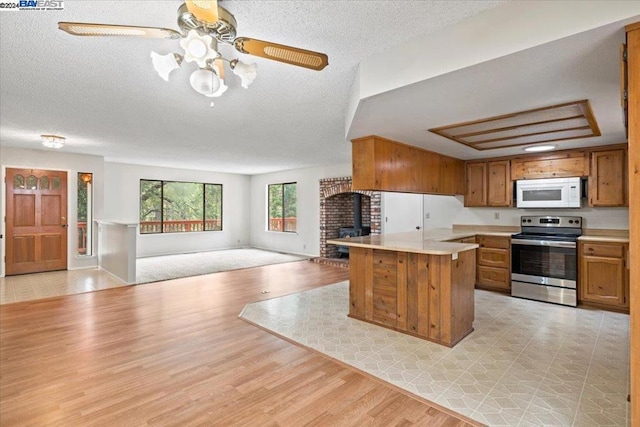 kitchen featuring a textured ceiling, ceiling fan, electric range, and light hardwood / wood-style flooring