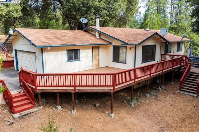 rear view of house with a wooden deck and a garage