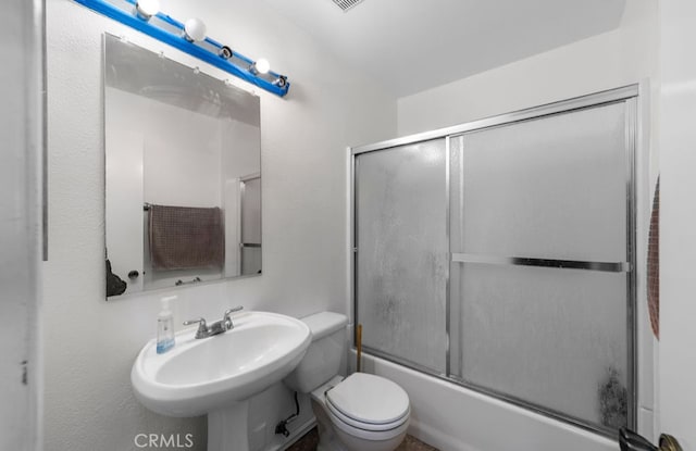 full bathroom with combined bath / shower with glass door, toilet, and sink