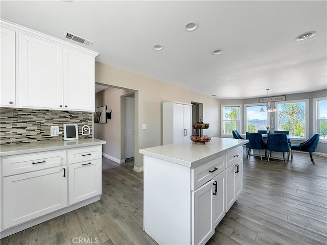 kitchen with hanging light fixtures, light hardwood / wood-style floors, white cabinets, backsplash, and a center island