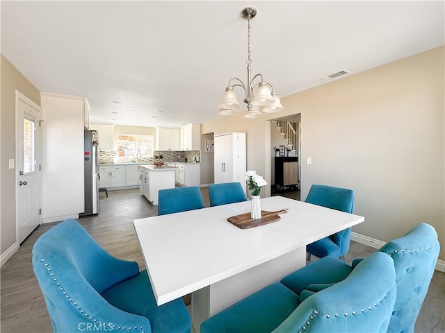 dining room featuring a notable chandelier, sink, and hardwood / wood-style flooring