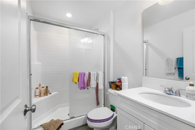 bathroom with a shower with door, vanity, and toilet