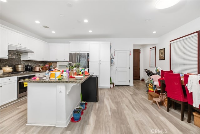 kitchen with a kitchen island with sink, stainless steel appliances, light hardwood / wood-style floors, and white cabinetry