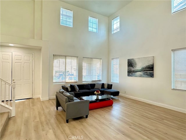 living room with light hardwood / wood-style floors and a high ceiling