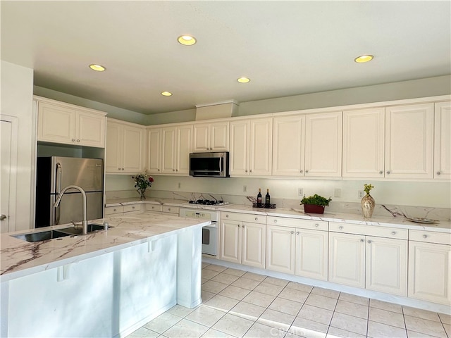 kitchen with white cabinetry, light stone countertops, light tile patterned floors, stainless steel appliances, and sink