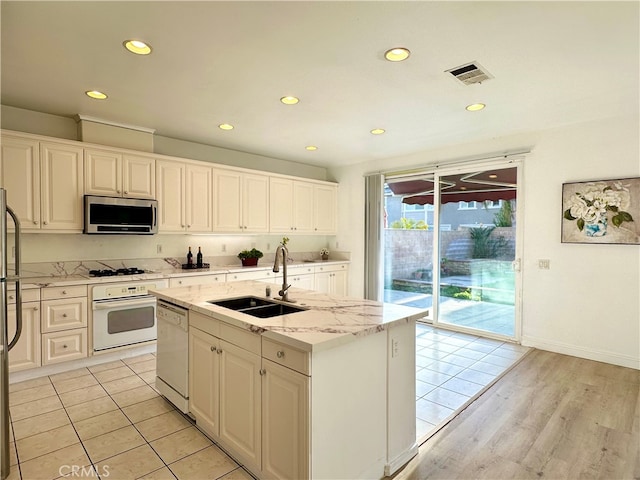 kitchen with white cabinets, an island with sink, sink, appliances with stainless steel finishes, and light wood-type flooring