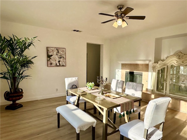 dining room featuring ceiling fan, hardwood / wood-style flooring, and a fireplace