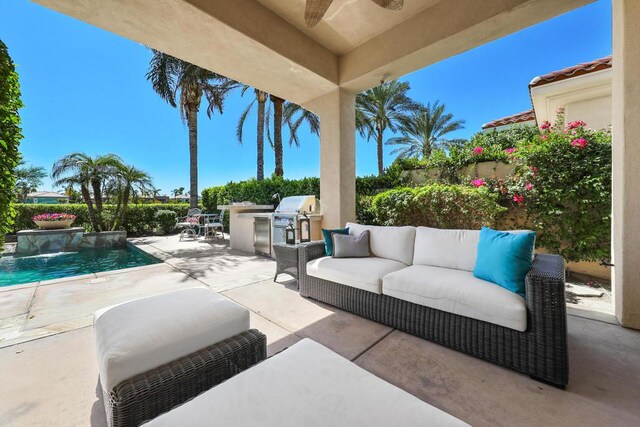 view of patio / terrace with pool water feature, area for grilling, and exterior kitchen