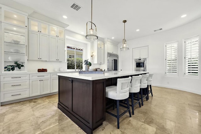 kitchen with pendant lighting, a healthy amount of sunlight, white cabinetry, and appliances with stainless steel finishes