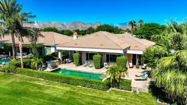 back of property with a lawn, a mountain view, area for grilling, and a patio area