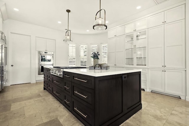 kitchen with white cabinets, appliances with stainless steel finishes, a center island, and decorative light fixtures