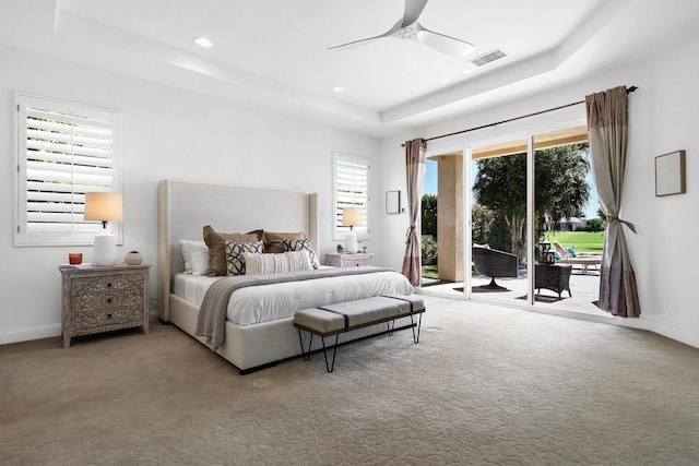 carpeted bedroom with a tray ceiling, access to exterior, and ceiling fan