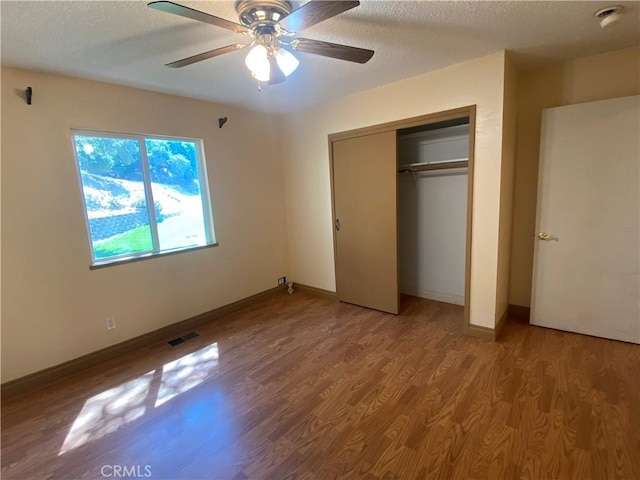 unfurnished bedroom with ceiling fan, a closet, a textured ceiling, and hardwood / wood-style flooring