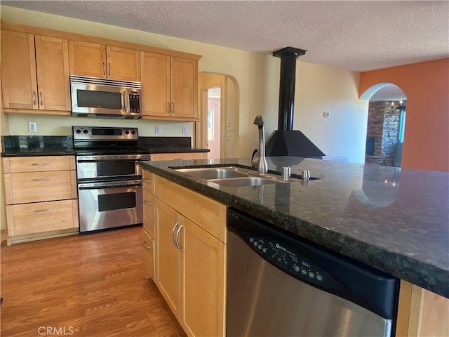 kitchen with light brown cabinets, light hardwood / wood-style floors, a textured ceiling, and appliances with stainless steel finishes