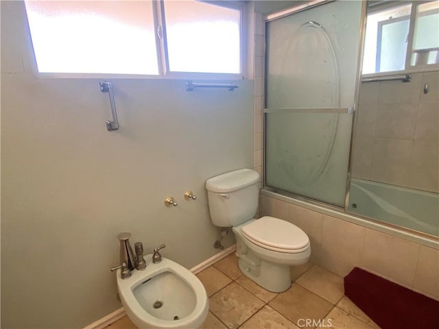 bathroom featuring tile patterned flooring, toilet, bath / shower combo with glass door, and a bidet