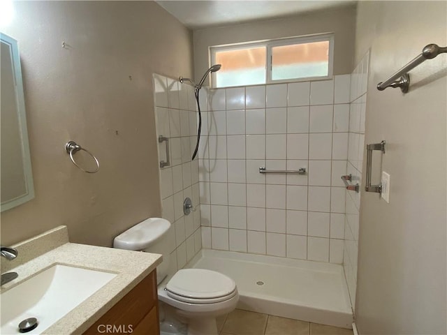 bathroom featuring tile patterned flooring, vanity, toilet, and a tile shower