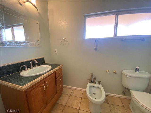 bathroom with tile patterned floors, toilet, a bidet, and a wealth of natural light