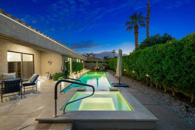 pool at dusk featuring an in ground hot tub, a patio area, and sink