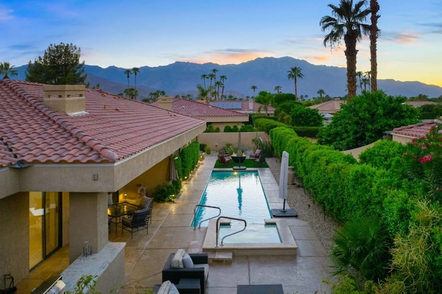 pool at dusk featuring a patio area and a mountain view