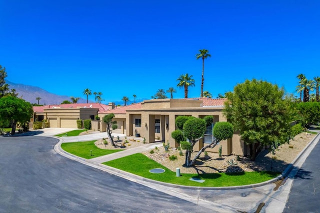 ranch-style home featuring a mountain view, a front lawn, and a garage