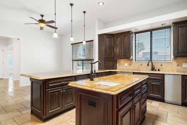 kitchen featuring decorative backsplash, ceiling fan, sink, decorative light fixtures, and a center island