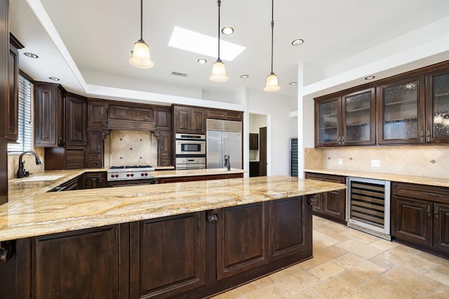 kitchen featuring pendant lighting, beverage cooler, sink, and appliances with stainless steel finishes