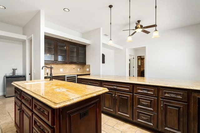 kitchen with pendant lighting, a center island, dark brown cabinetry, and beverage cooler