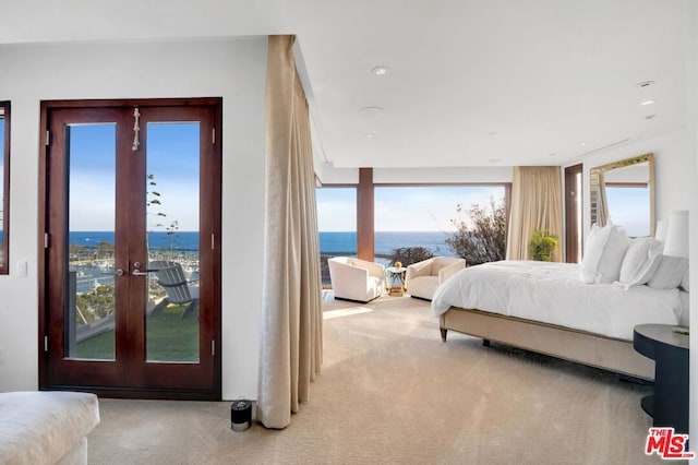 carpeted bedroom featuring french doors, multiple windows, and a water view