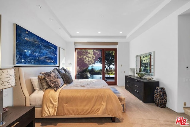 carpeted bedroom with access to outside and a tray ceiling