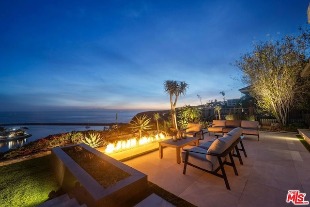 patio terrace at dusk with a water view and an outdoor fire pit