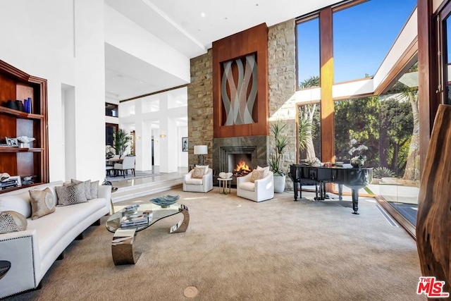 living room featuring carpet floors, a towering ceiling, and a large fireplace