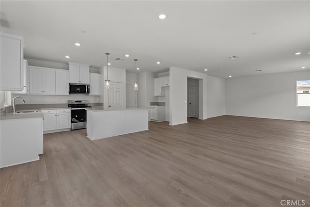 kitchen featuring appliances with stainless steel finishes, white cabinets, a center island, and light hardwood / wood-style floors