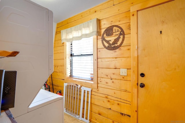 clothes washing area featuring stacked washer / drying machine and wood walls