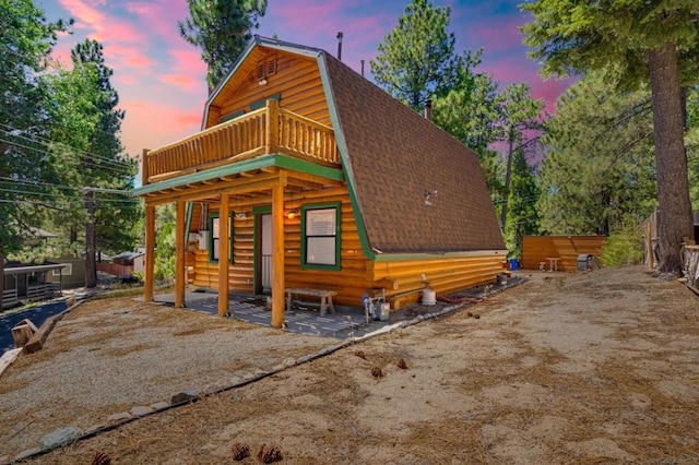 back house at dusk featuring a balcony