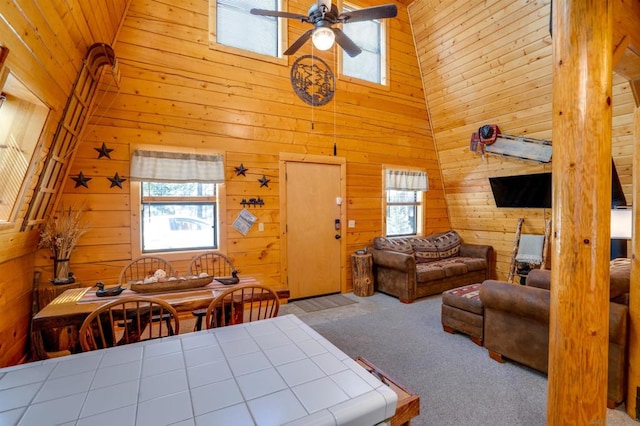 interior space with ceiling fan, wood walls, and high vaulted ceiling