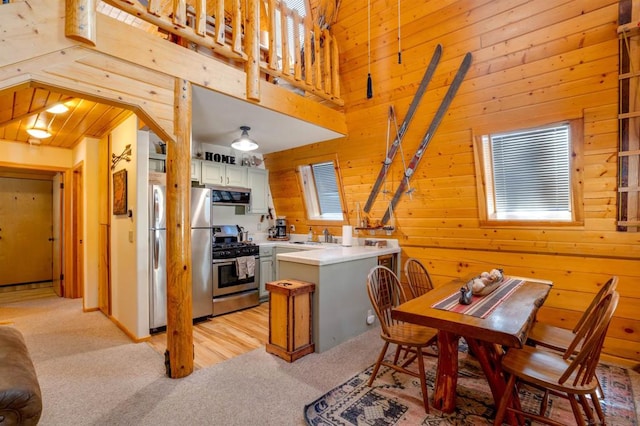 interior space featuring wood walls, light carpet, stainless steel appliances, and white cabinets