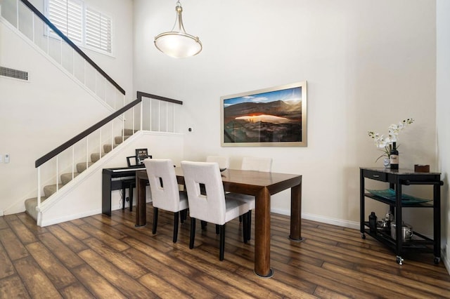 dining space featuring a high ceiling and dark wood-type flooring